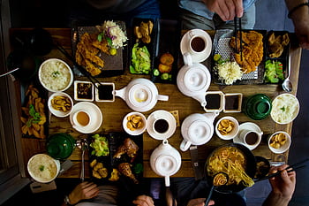 A vibrant spread of traditional Taiwanese dishes with teapots and sides on a wooden table. HD wallpaper