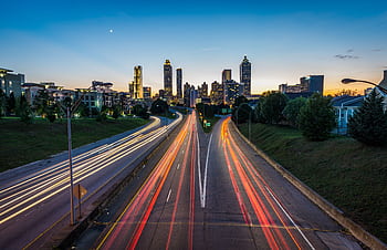 Stunning dusk view of Atlanta skyline with light trails on a busy highway, capturing urban vibrancy. HD wallpaper