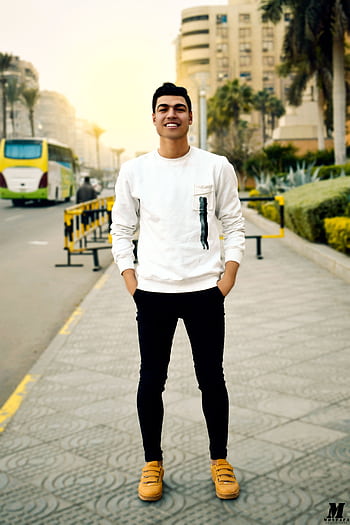 Smiling young man posing confidently on a city street during the day. HD phone wallpaper