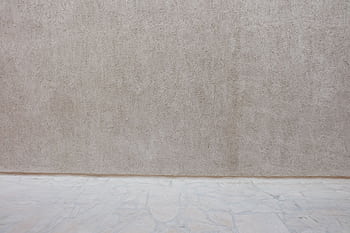 A beige textured wall paired with a stone floor, offering a neutral background. HD wallpaper