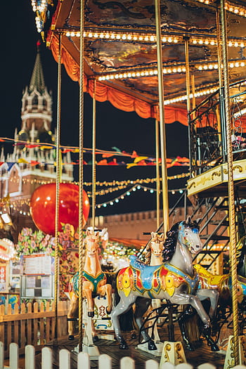 Vibrant carousel horses illuminated during Moscow's festive night celebration. HD phone wallpaper