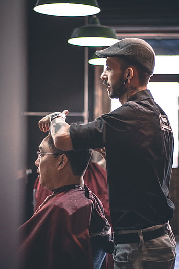 Barber skillfully trims customer's hair in a modern salon, capturing hairstyle expertise. HD phone wallpaper