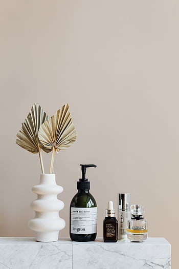 Minimalist bathroom shelf featuring skincare bottles and decorative beige vase. HD phone wallpaper