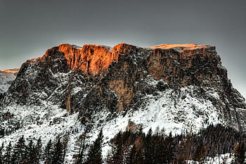 Stunning snow-capped mountain peak illuminated by the warm glow of sunset, scenic and serene. HD wallpaper
