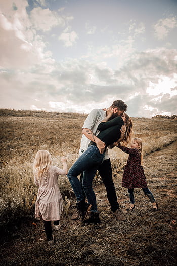A joyful family shares a loving moment outdoors, surrounded by nature. HD phone wallpaper