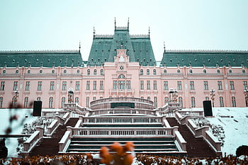 A majestic pink palace surrounded by snow, showcasing elegant architecture. HD wallpaper