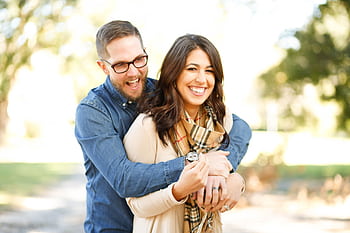 A happy couple enjoying an outdoor engagement hoot with laughter and love. HD wallpaper