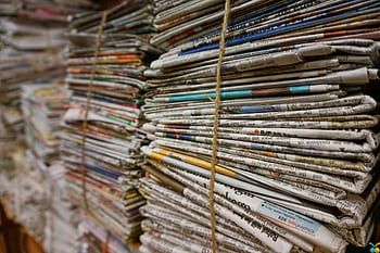 Close-up view of stacked newspapers tied with twine, ideal for recycling and storage concepts. HD wallpaper