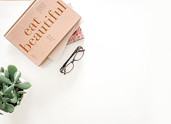 A minimalist flatlay featuring a book, eyeglasses, and a plant on a white background. HD wallpaper