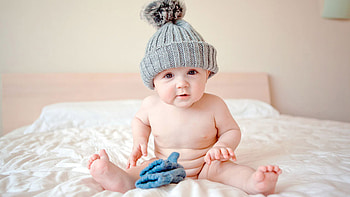 Cute Child Baby Is Sitting On White Bed Wearing Ash Woolen Knitted Cap Cute HD wallpaper