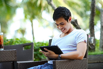 Happy young man enjoying leisure time outdoors using a tablet. HD wallpaper