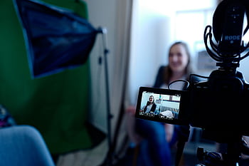 Woman being recorded in a professional studio setup, using video camera and lighting equipment. HD wallpaper