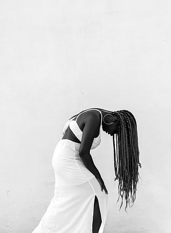 Graceful black woman in a white dress striking a pose, exuding elegance and balance. HD phone wallpaper