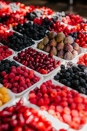 Colorful display of assorted fruits including berries and figs at a local market. HD phone wallpaper