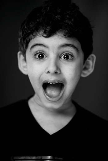 A monochrome portrait of a surprised young boy with wide eyes and open mouth. HD phone wallpaper