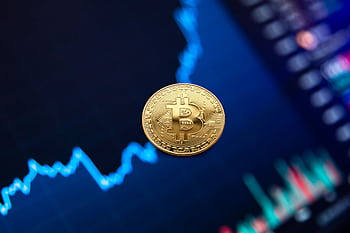 A gold Bitcoin coin against a backdrop of a digital financial chart, symbolizing cryptocurrency trading. HD wallpaper