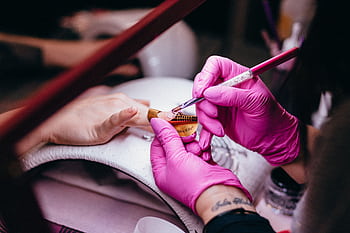 Close-up of a nail technician applying nail art in a beauty salon setting, highlighting precision and artistry. HD wallpaper