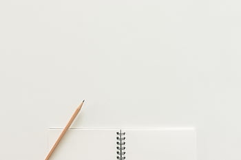 A top view of a spiral notebook with pencil on a neutral light background, ideal for creative workspaces. HD wallpaper