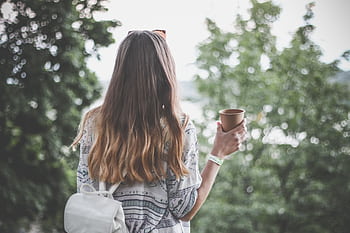 Back view of a young woman with long hair holding a coffee cup outdoors in a tranquil park. HD wallpaper