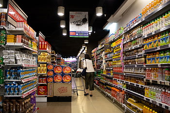 Vibrant supermarket aisle scene with a shopper in Jawa Timur, Indonesia. HD wallpaper