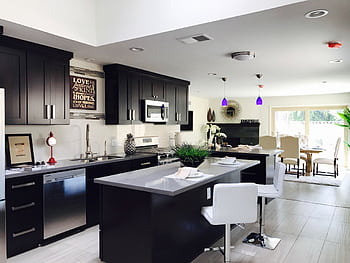 Sleek open-plan kitchen with modern decor, featuring stainless appliances and bar seating. HD wallpaper