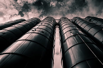 Low angle view of industrial silos with a dramatic cloudy sky in the background, emphasizing modern industry. HD wallpaper