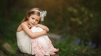 Cute Little Girl Is Sitting On Wood Bench Wearing Light Peach Color Dress In Blur Background Cute HD wallpaper