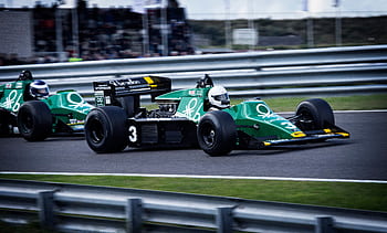 Action-packed shot of classic Formula 1 cars racing on a speedway, showcasing speed and competition. HD wallpaper