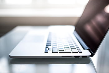 Elegant side view of a laptop on a glossy table with natural lighting indoors. HD wallpaper