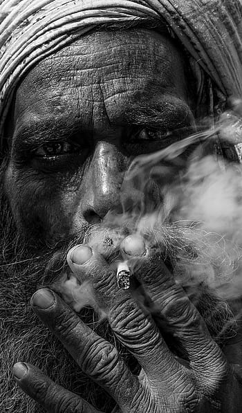 A powerful black and white close-up portrait of an elderly man smoking, showcasing wrinkles and texture. HD phone wallpaper