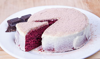 Sliced red velvet cake with cream cheese frosting on a white plate, perfect for dessert lovers. HD wallpaper