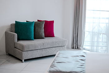 Simple modern interior featuring a grey sofa with vibrant colored cushions in a bright room. HD wallpaper