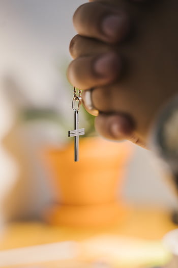 Close-up of hands clasped in prayer holding a cross pendant with blurred background. HD phone wallpaper