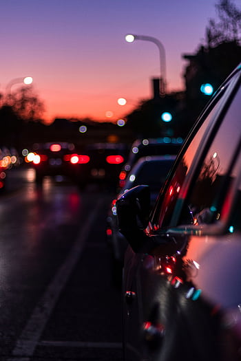 Blurred city street scene at dusk with vibrant lights reflecting on car surface, capturing nightlife essence. HD phone wallpaper