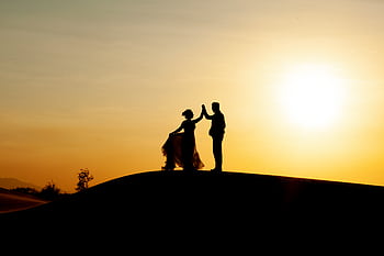 Silhouetted couple dancing on the beach during a golden sunset, creating a romantic scene. HD wallpaper