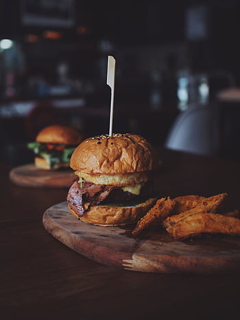 Delicious gourmet beef burger served with crispy sweet potato fries on a rustic wooden board. HD phone wallpaper
