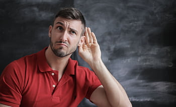 Thoughtful man listening intently against a chalkboard background in a red polo shirt. HD wallpaper