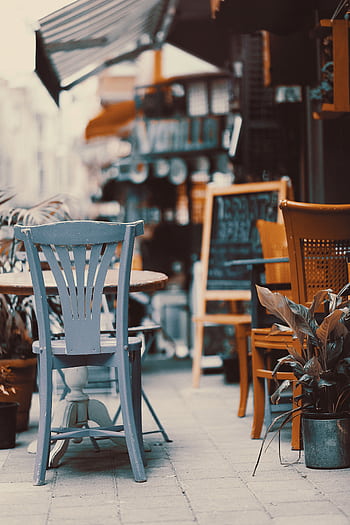 Cozy outdoor cafe with vintage chairs and tables on a sunny street. Perfect spot to relax. HD phone wallpaper