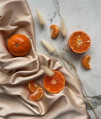 Top view of fresh sliced oranges placed on silky fabric with dried grasses, offering a natural and healthy vibe. HD phone wallpaper