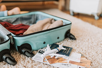Close-up of an open suitcase with travel essentials like passport and tickets, ready for a journey. HD wallpaper