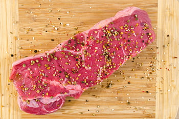 Close-up of a raw steak with spices on a wooden cutting board, perfect for cooking inspirations. HD wallpaper