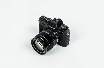 Close-up of a Fujifilm camera with lens on a plain background, showcasing graphic equipment. HD wallpaper