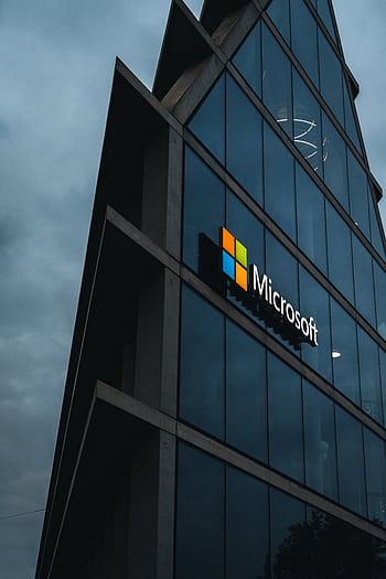 A modern Microsoft office skyscraper with glass facade against a cloudy evening sky. HD phone wallpaper