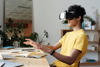 Teenager wearing a VR headset and interacting in a home setting, enjoying virtual reality experience. HD wallpaper