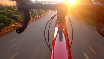 Experience the thrill of cycling at sunset, capturing speed and motion on a scenic road. HD wallpaper