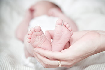 Tender of a mother's hands holding her newborn's feet, symbolizing love and care. HD wallpaper