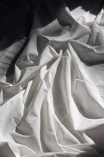 Soft white bed sheets with natural light and shadows creating a serene atmosphere. HD phone wallpaper
