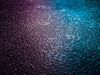 Close-up of vibrant water droplets on a textured surface, featuring pink and blue gradient lighting. HD wallpaper