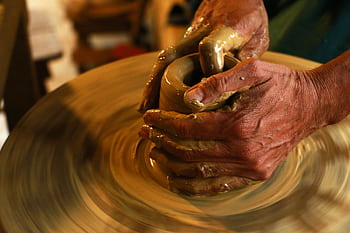 Close-up of hands shaping clay on a pottery wheel, highlighting the art of ceramics. HD wallpaper