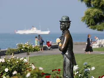 Switzerland - Charlie Chaplin statue, boat, sea, people, charlie chaplin, statue, tree, lake, park, rose, flower, view, water, switzerland HD wallpaper